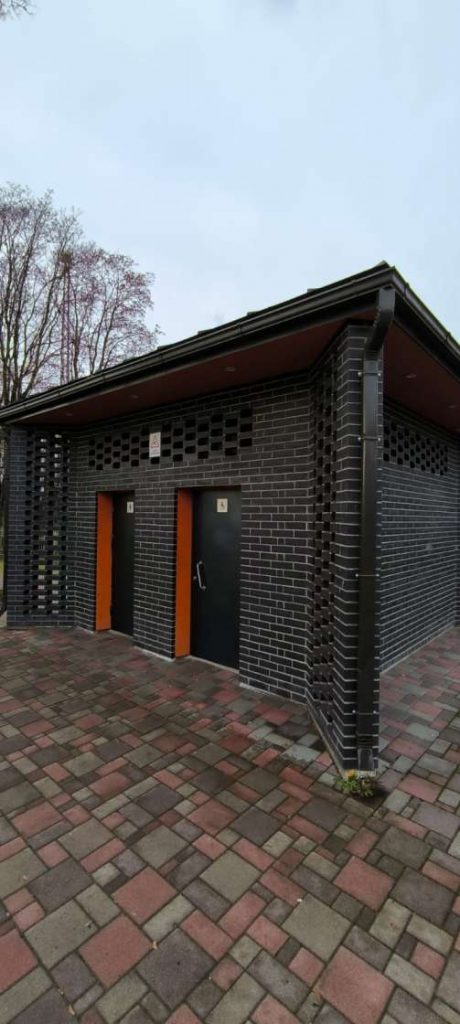 Tumšas krāsas publiskā tualete Kena parkā