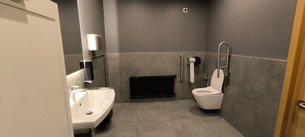 Kafejnīcas "Ķēķis" tualetes telpa pelēkā krāsā, pods un izlietne baltās krāsās