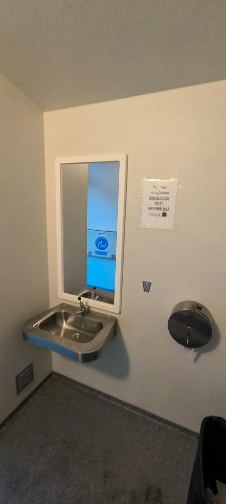 Publiskās tualetes dzelzs izlietne, ir spogulis un tualetes papīra turētājs