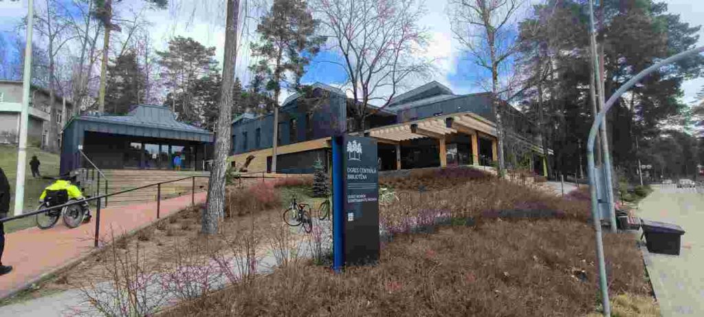 Pa sarkanas krāsas stāvu uzbrauktuvi Voldemārs cenšas tikt līdz bibliotēkas, kas ir no koka, ieejai