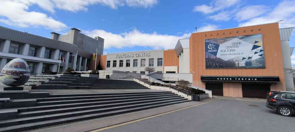 Fonā pelēkas un sarkanas krāsas paneļu ēka