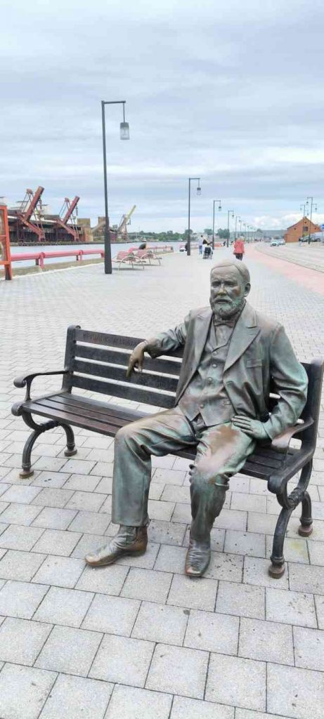 Promenādē uz dzelzs soliņa vides objekts - vīrietis sēž