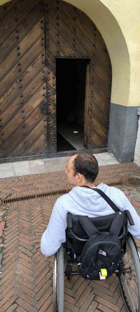 Voldemārs pie pils duvīm. Durvis no koka, priekšā bruģēts celiņš